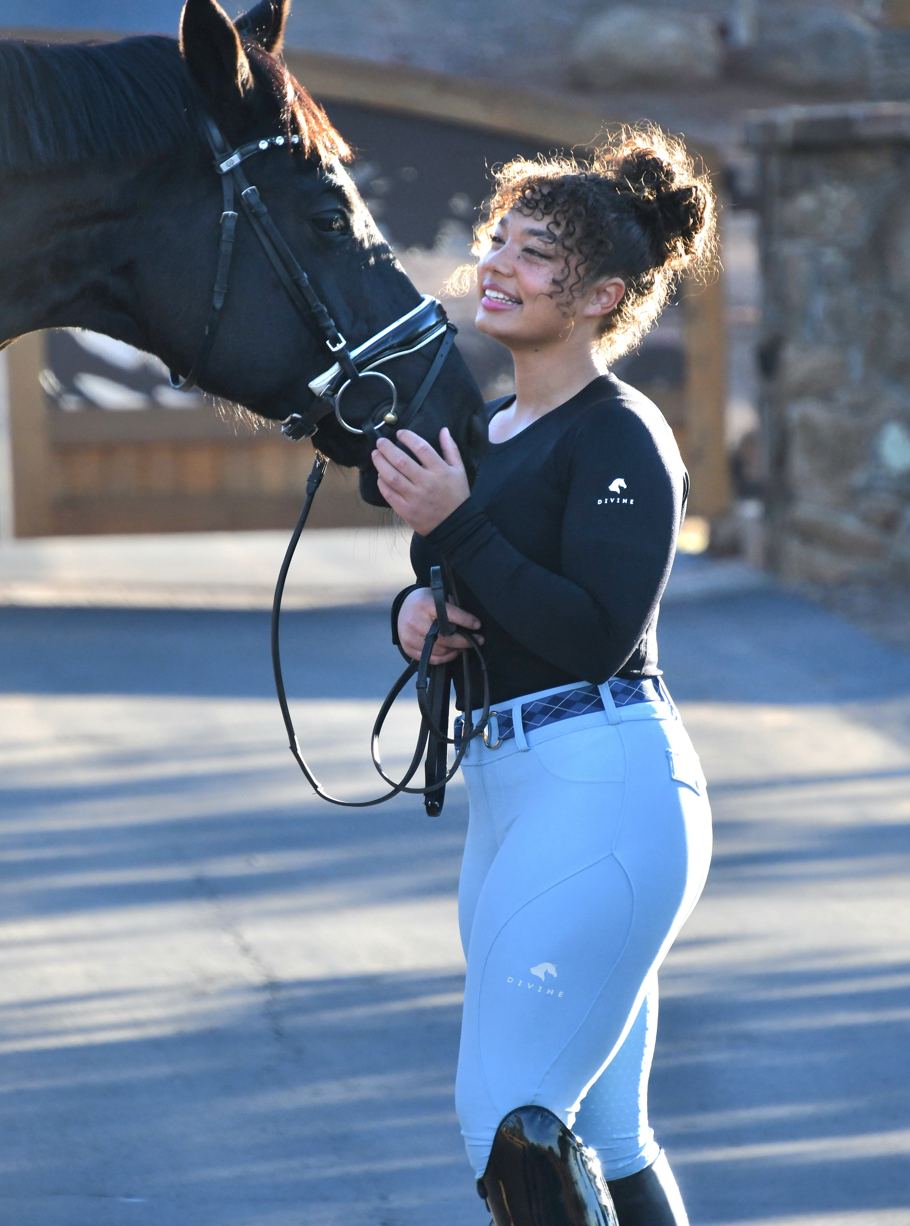Divine Equestrian Sponsored Rider Emme Chisholm wearing the Black Chic Athletic Long Sleeve Shirt, Blue Argyle Comfort Fit Belt, and Sky Blue Comfort Grip Leggings