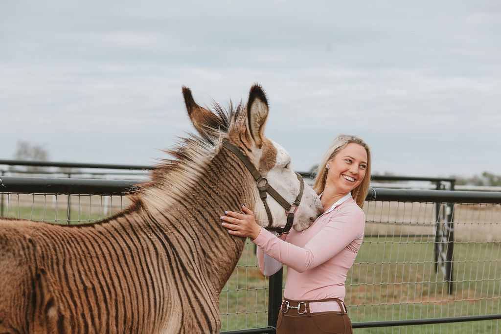 Zebediah the Zedonk, Divine Equestrian's mascot with the founder who is wearing the pink Sweet Lady Sun Shirt, Unicorn Pink Elastic Belt, and Mocha Comfort Grip Leggings