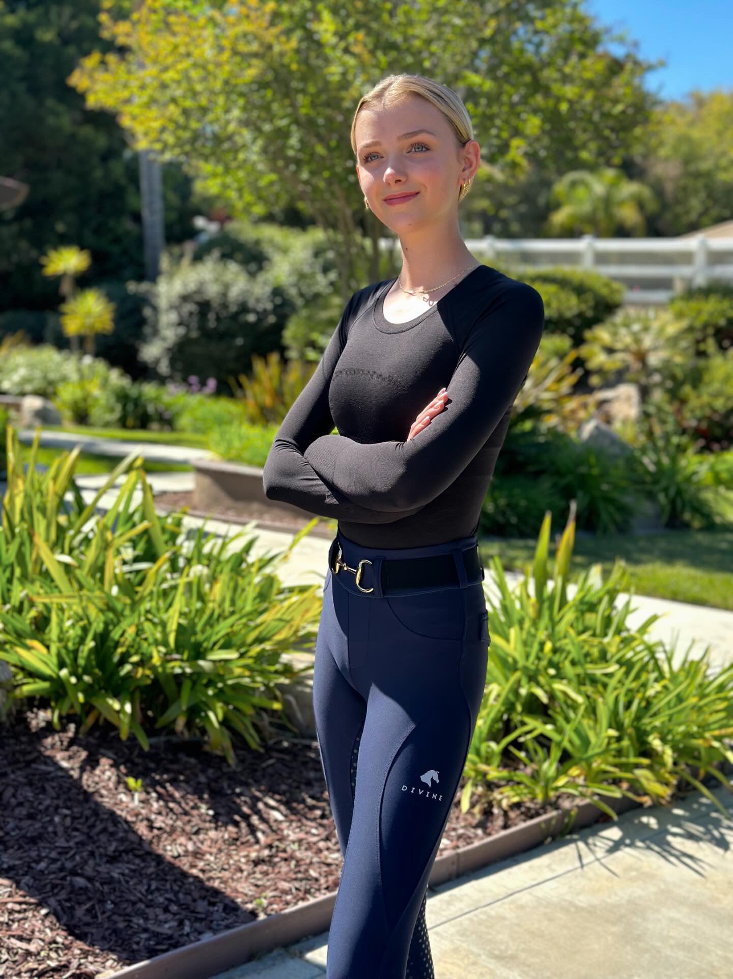 Sofie Holmes wearing Divine Equestrian Black Chic Athletic Long Sleeve Shirt, Black Comfort Fit Belt, and Navy Comfort Grip Leggings